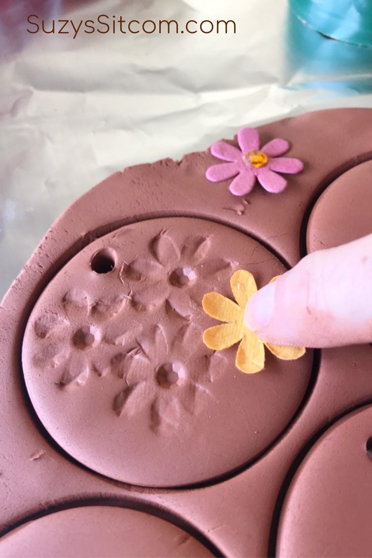 Pressing floral shapes into the wet clay 