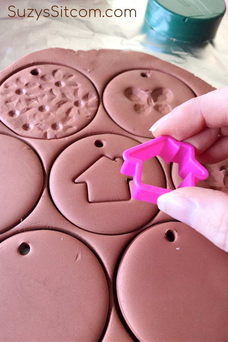 Using a tiny cookie cutter to put a shape into the wet clay 