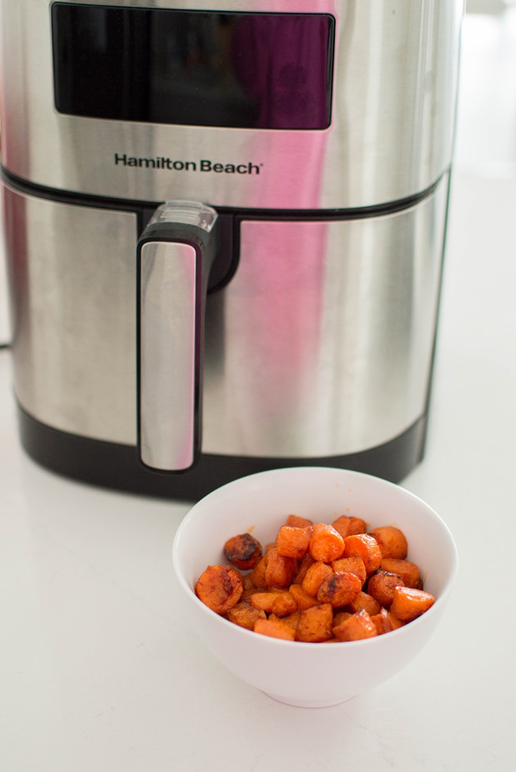Bowl of carrots in front of a Hamilton Beach air fryer.