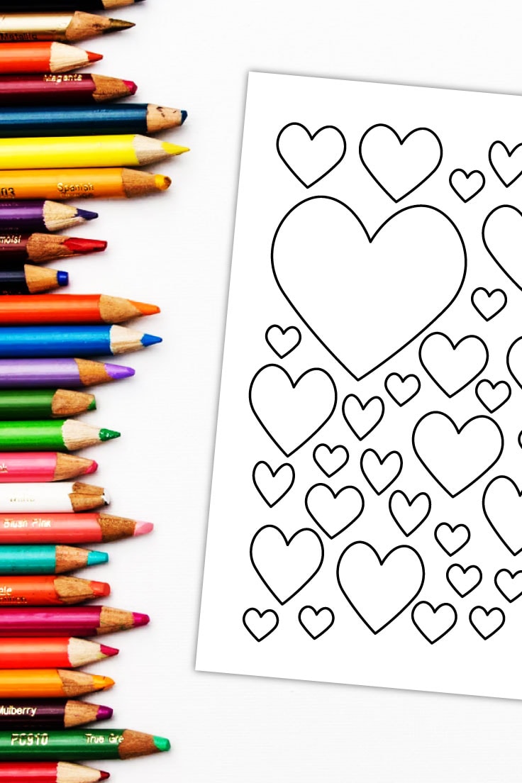 Preview of mixed heart design page on white desk with row of colored pencils on the left.