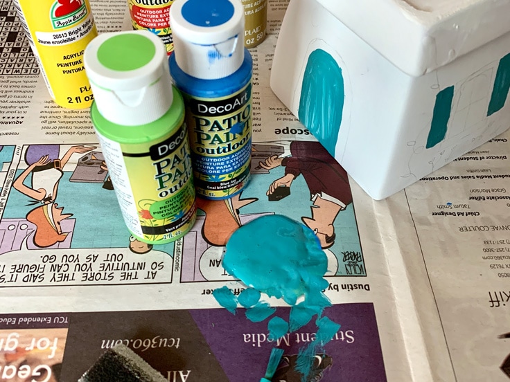 Mixing blue and green acrylic paint to create turquoise.