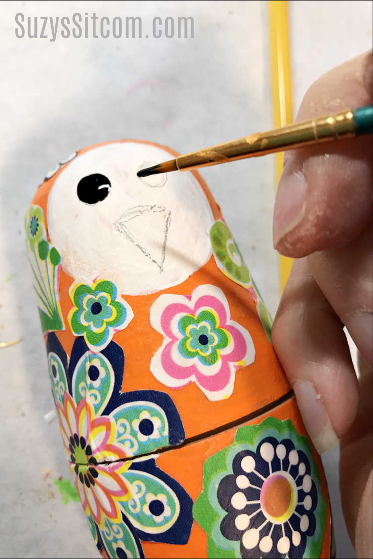 Painting eyes and a beak on the wooden nesting birds 