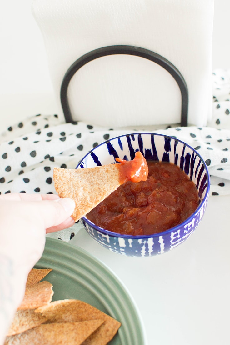 Dipping homemade air fryer chips into a bowl of salsa.