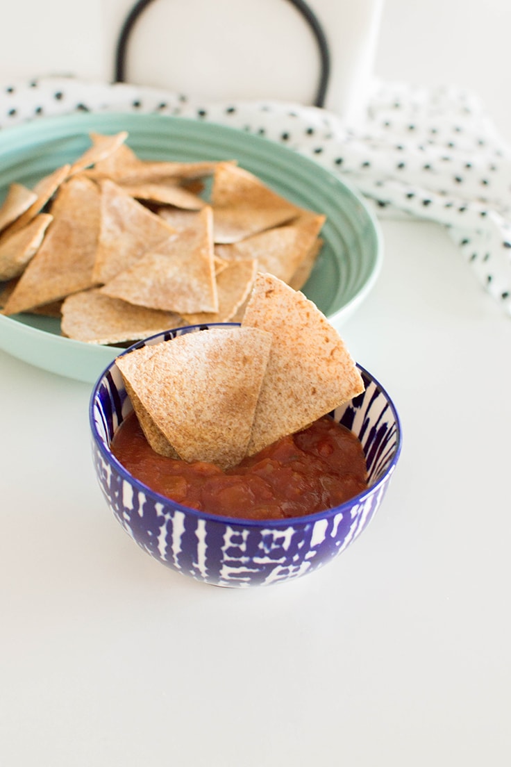 3 tortilla chips sitting in a bowl of salsa.
