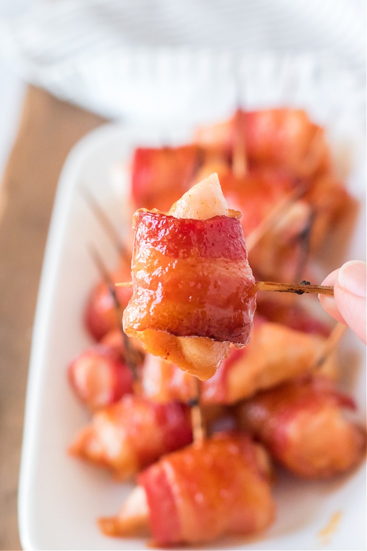 Closeup of bacon wrapped around a piece of chicken on a toothpick.
