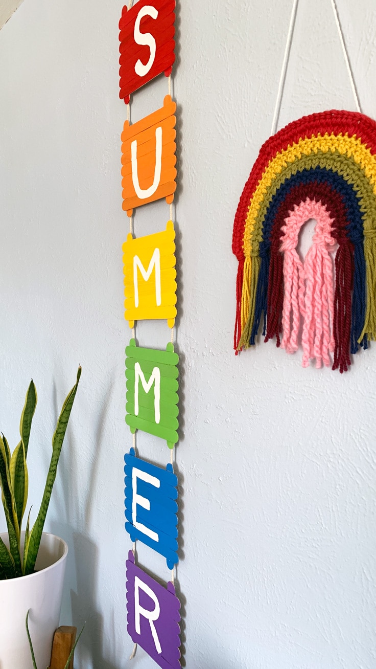 Closeup of popsicle stick decor made from painting popsicle sticks in rainbow colors for each letter in SUMMER.