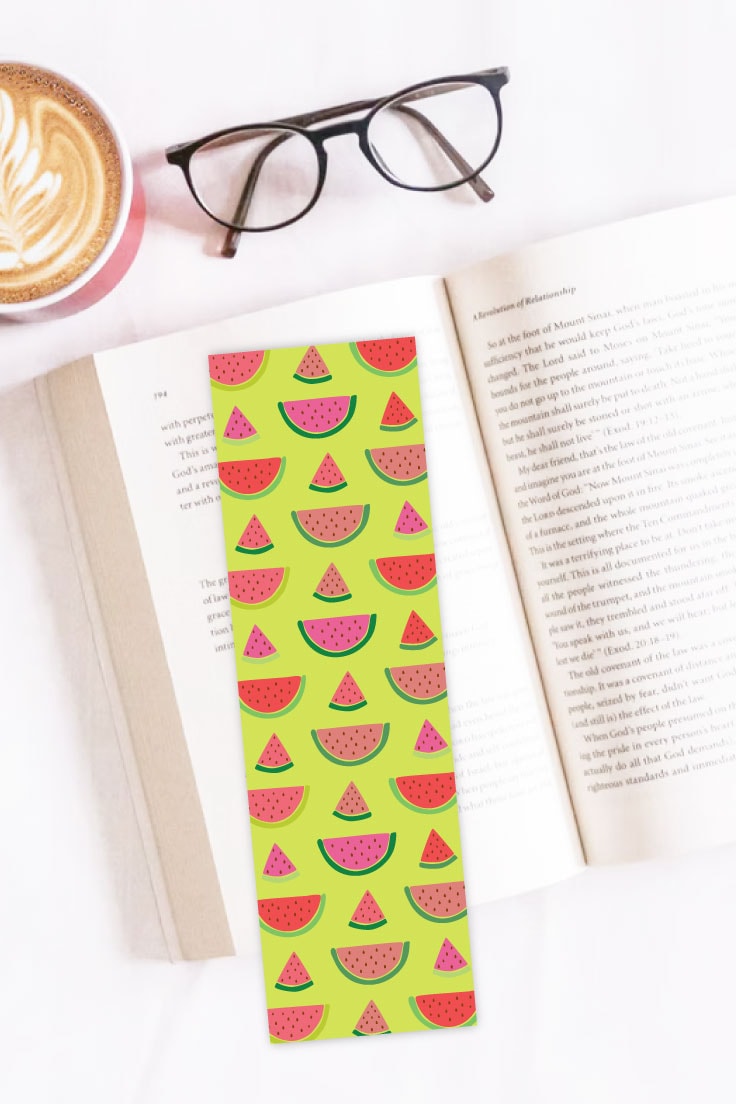 Preview of watermelon printable bookmark on to of an open book on white table with mug of coffee and showing glasses above.