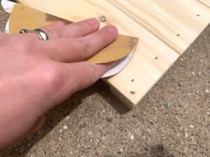 Hand sanding a piece of unfinished pine wood.