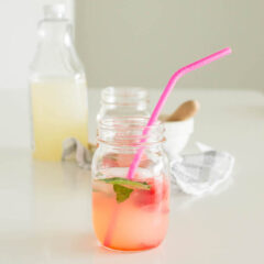 A mason jar filled with Strawberry Basil Lemonade and topped off with a pink straw