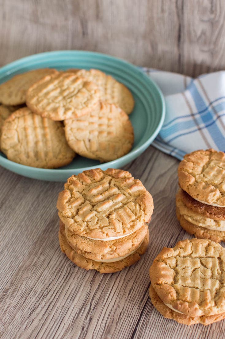 Bird's eye view of Peanut Butter Sandwich Cookies stacked on top of each other, with more cookies in the backgroundanut Butter Sandwich Cookies next to a mint green bowl.