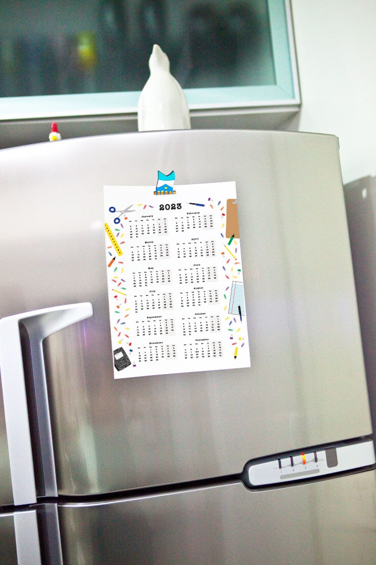 Preview of yearly 2023 calendar printable one page stuck on silver refrigerator door in kitchen.