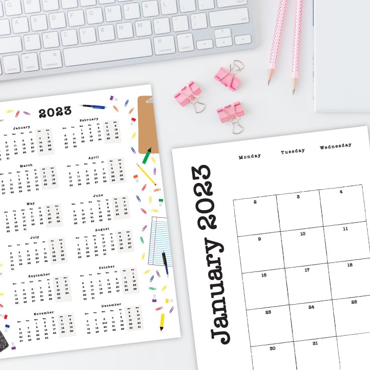 Preview of yearly and monthly calendar printables on white esk with keyboard and pink stationery clips and pens on top.