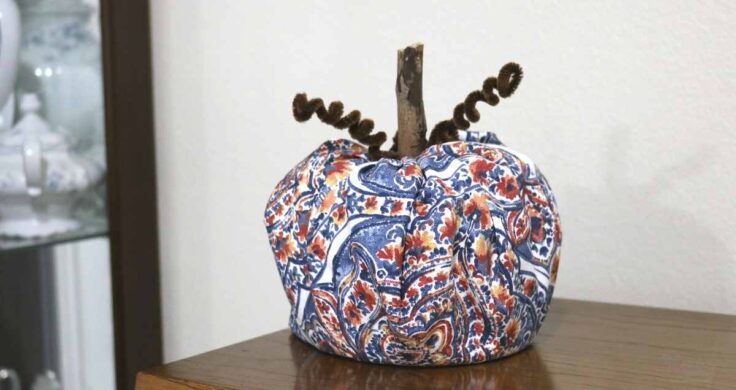 Blue and orange fall home decor- a blue and orange fabric toilet paper roll pumpkin on a piano