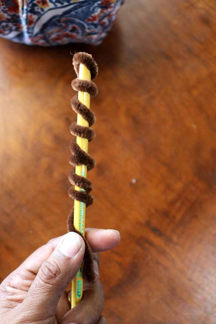 brown pipe cleaner coiled around pencil to form pumpkin craft tendrils