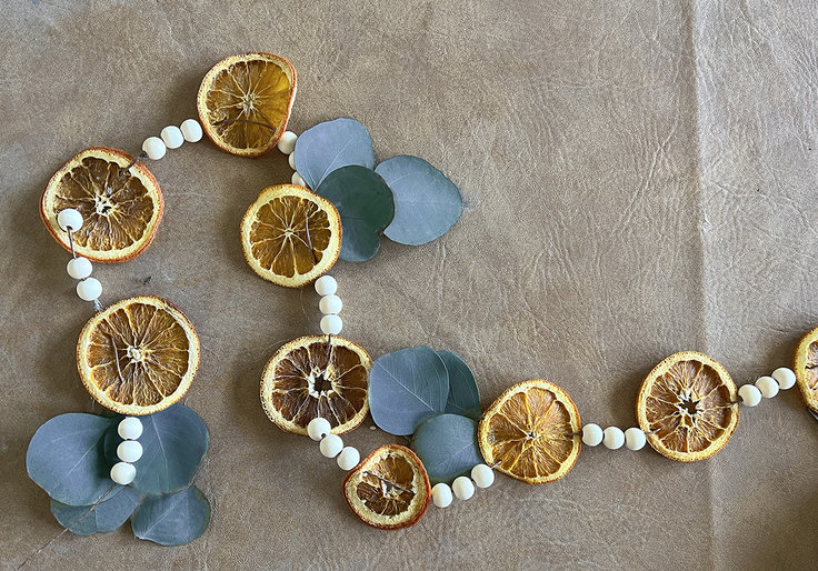 A homemade orange and blue garland with white wooden beads and dried orange slices. 