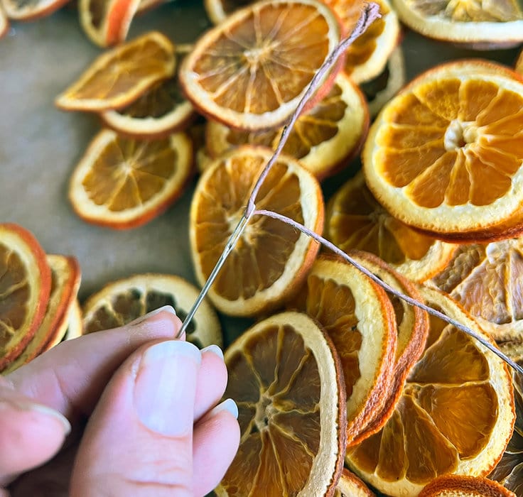 Use a needle to thread dried orange slices on the garland 