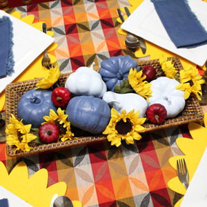 Faux pumpkins spray painted blue and red in a basket with silk sunflowers.