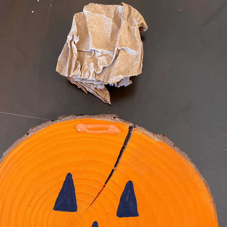 Top of a wood slice pumpkin with hot glue on the front and a stem sitting above it.