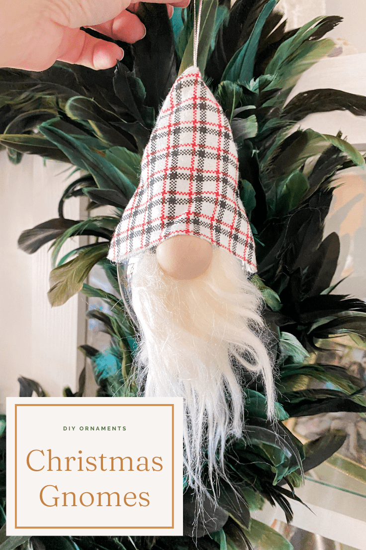 Gnome ornament with red, black, and white hat, hanging in front of a feather wreath.