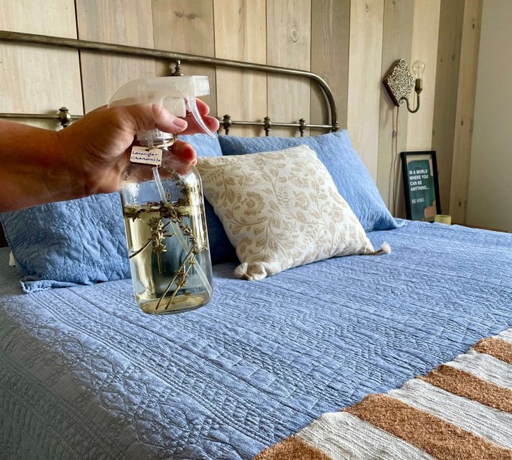 DIY Room spray used as a linen spray in a bedroom with a blue quilt.