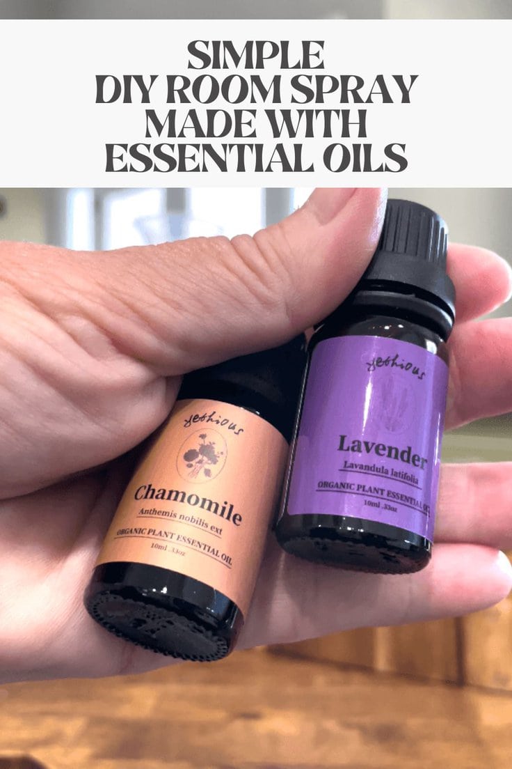 Hand holding bottles of essential lavender and chamomile oils.