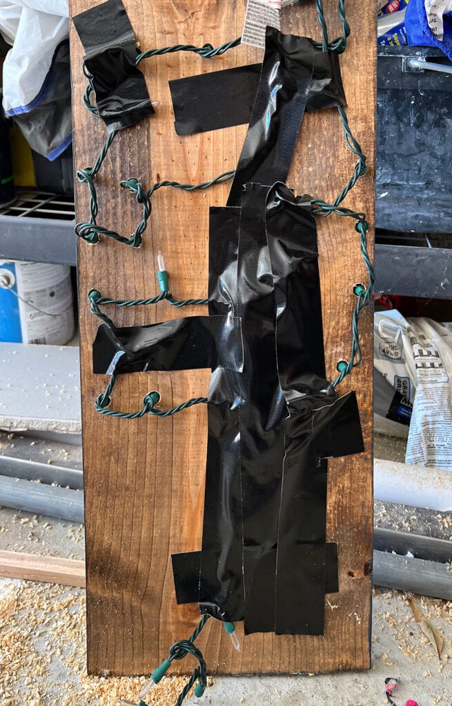 black duct tape keeps the christmas tree lights secured on the back of the sign and organized so that the long light strand isn't just hanging there.
