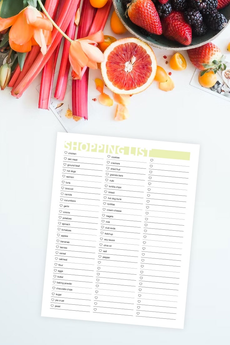 Preview of printable grocery list on white background with a variety of fruits and vegetables on top. 