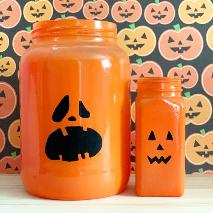 Glass jars painted orange with jack o'lantern faces.