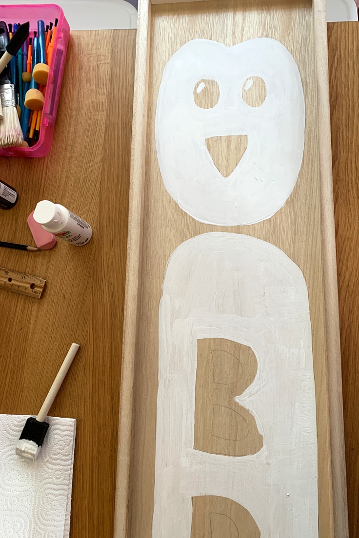 A white penguin face and body painted on wood.