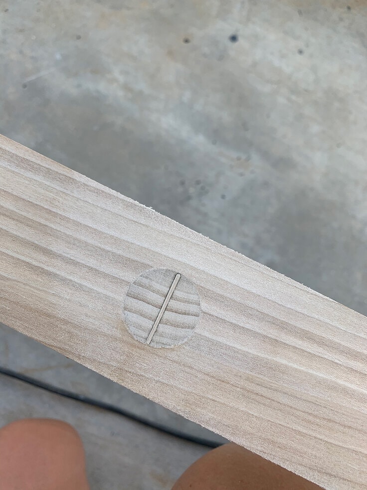 zoomed in picture of the dowel joint with the shim wedge sanded smooth and ready for staining on our diy solid wood blanket ladder.
