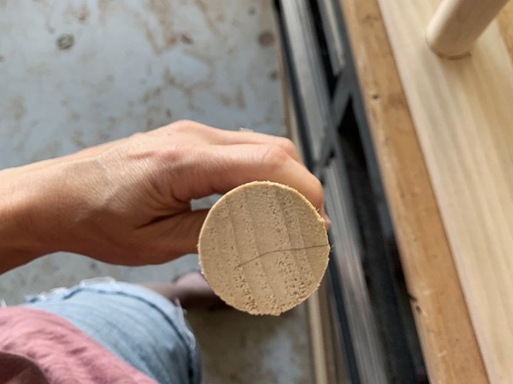 Joannie is holding the dowel or ladder rung so that you can see the end of it and the direction the grain is flowing. She marked perpendicular to the grain so you can see which direction to cut a relief kerf.