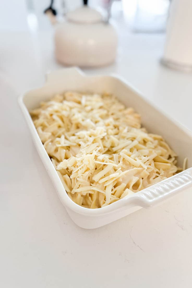Egg Noodles Mac and Cheese in a white casserole dish ready to be baked in the oven