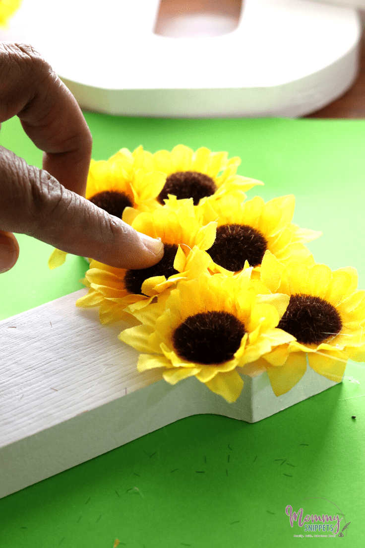 gluing artificial flowers onto the wood letter