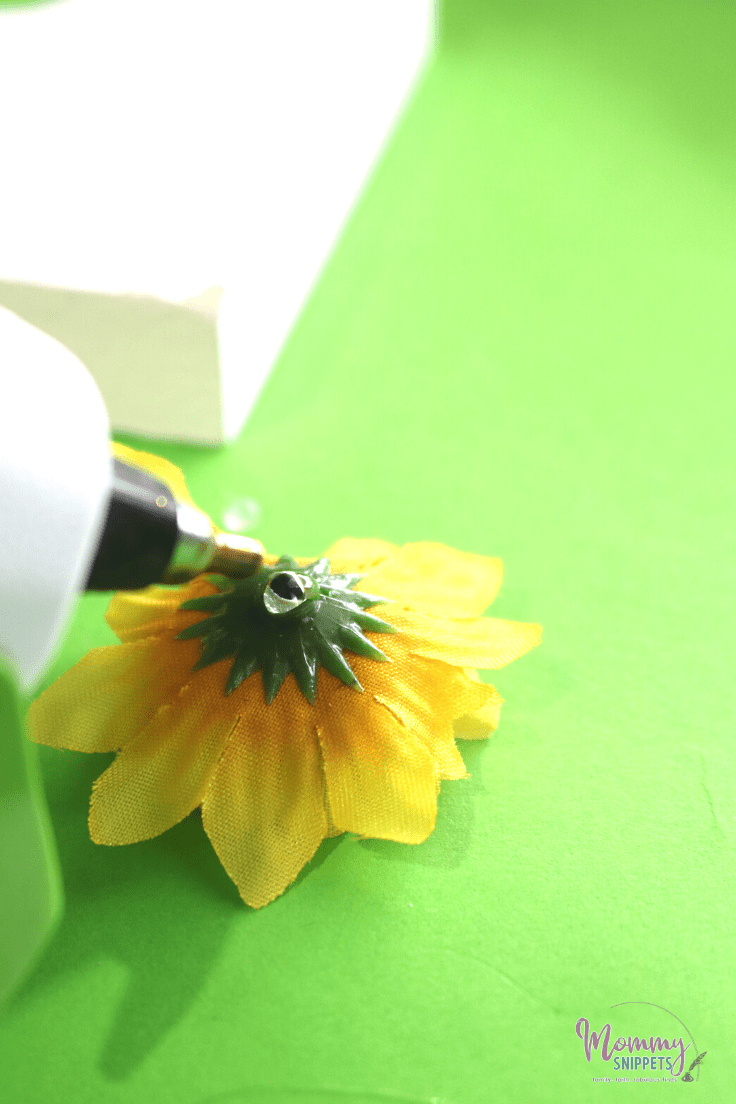 Adding hot glue onto the back of any artificial flower- a floral letter craft tutorial