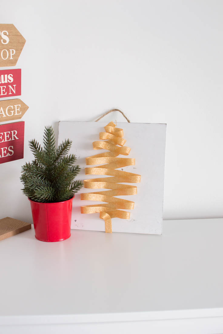 Our very own holiday-themed door hanger sitting on a white table with other Christmas decor