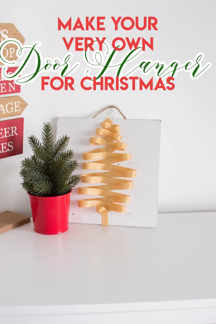 Our very own holiday-themed door hanger sitting on a white table with other Christmas decor.