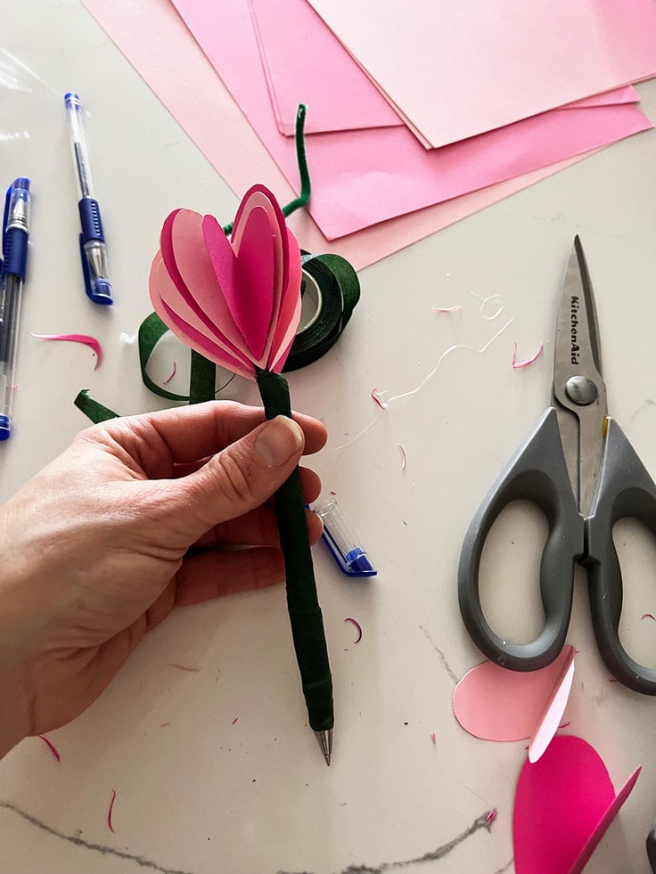 The hearts are secured to the pen with pipe cleaner and finished with floral tape, the floral tape stops just short of where the pend cap goes on so that the pen can still be capped.