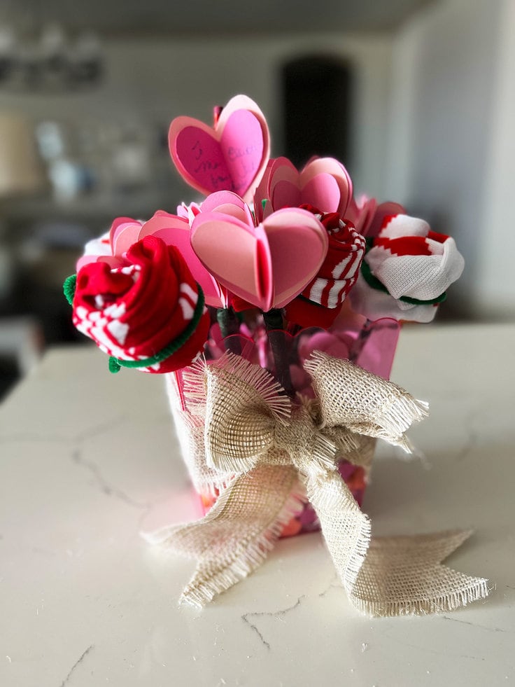 sock rose buds and hearts made from card stock and attached to pens create arrows for this valentine heart bouquet.