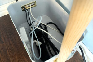 Inside view of a decorative box hiding a surge protector and several long cords plugged into it.