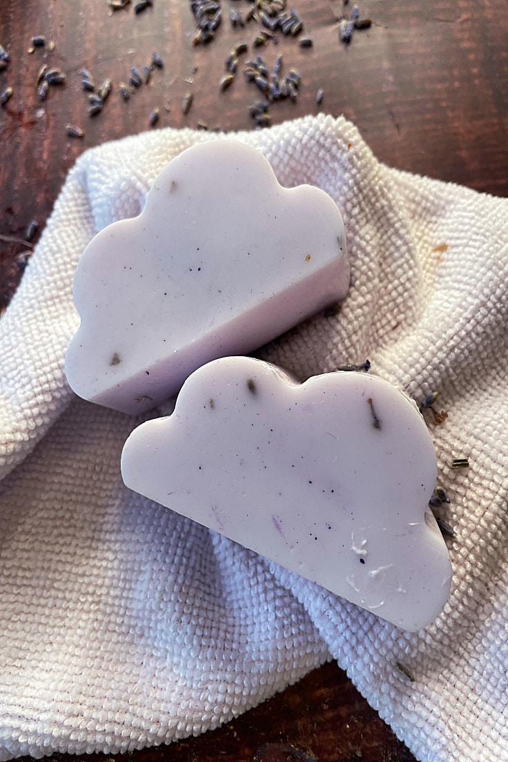cloud shaped lavender soap on white wash cloth on a dark table
