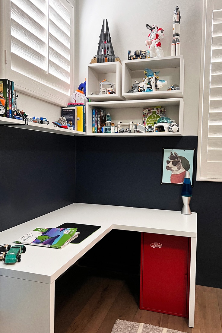 pull away shot of shadow box shelves over built in corner desk in kids room with color block design.