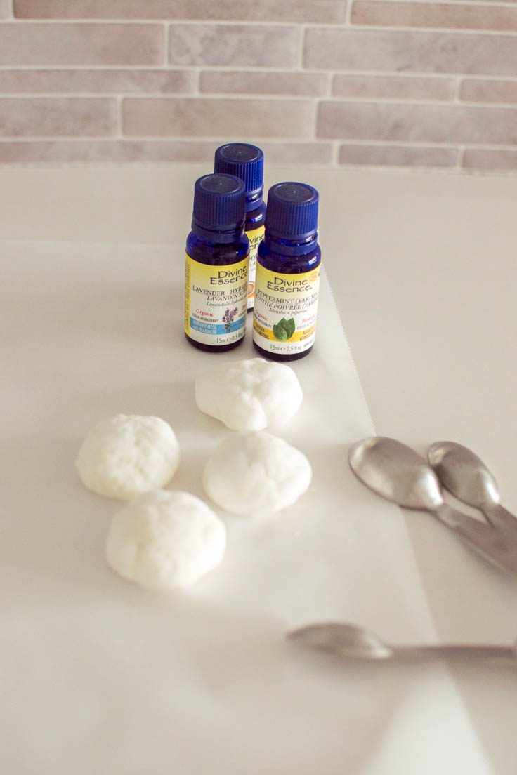 Four shower steamers sitting on parchment paper with essential oil bottles in the background