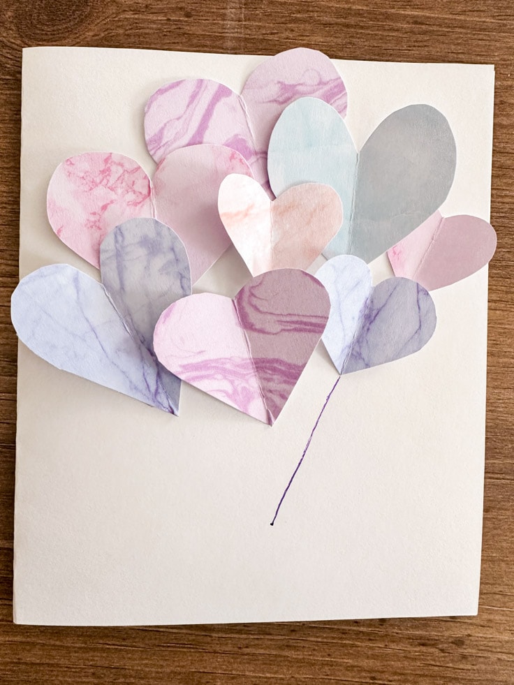 Multiple color hearts on a white card with purple pen one heart
