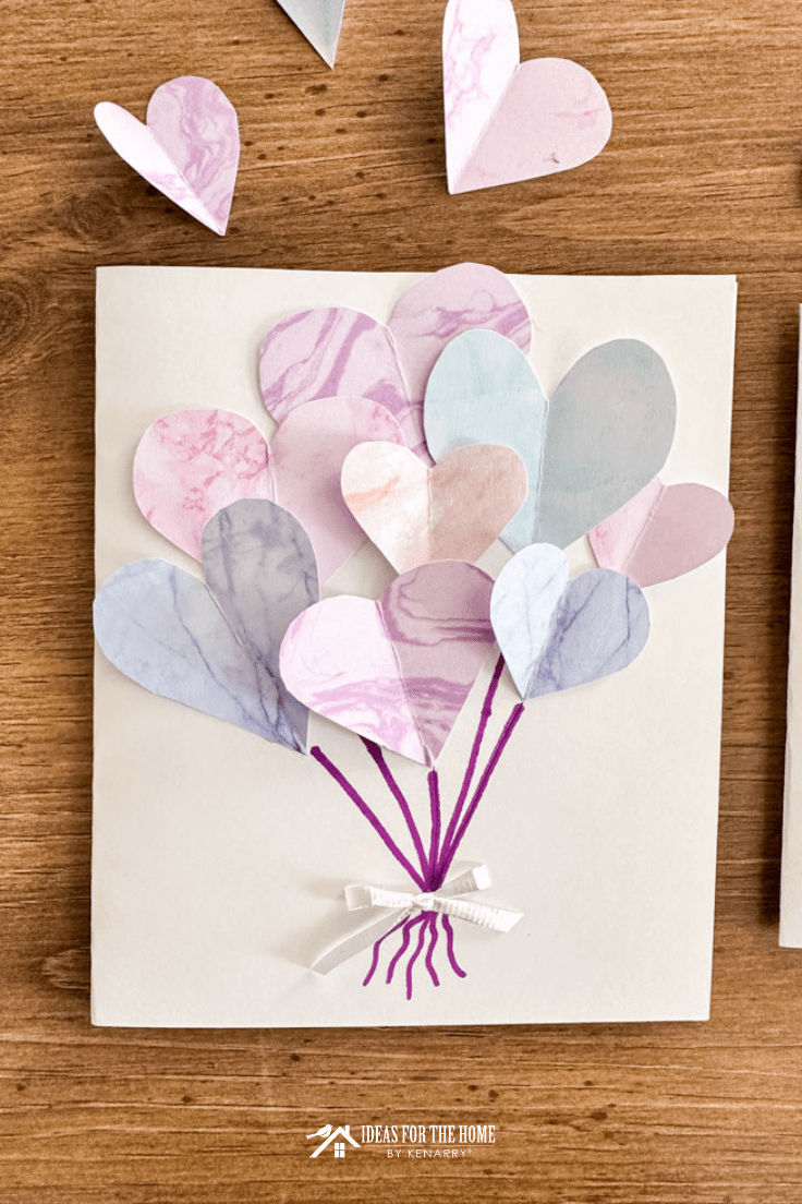 Multiple color hearts on a white card with purple pen drawn to each heart and a white bow holding them all together