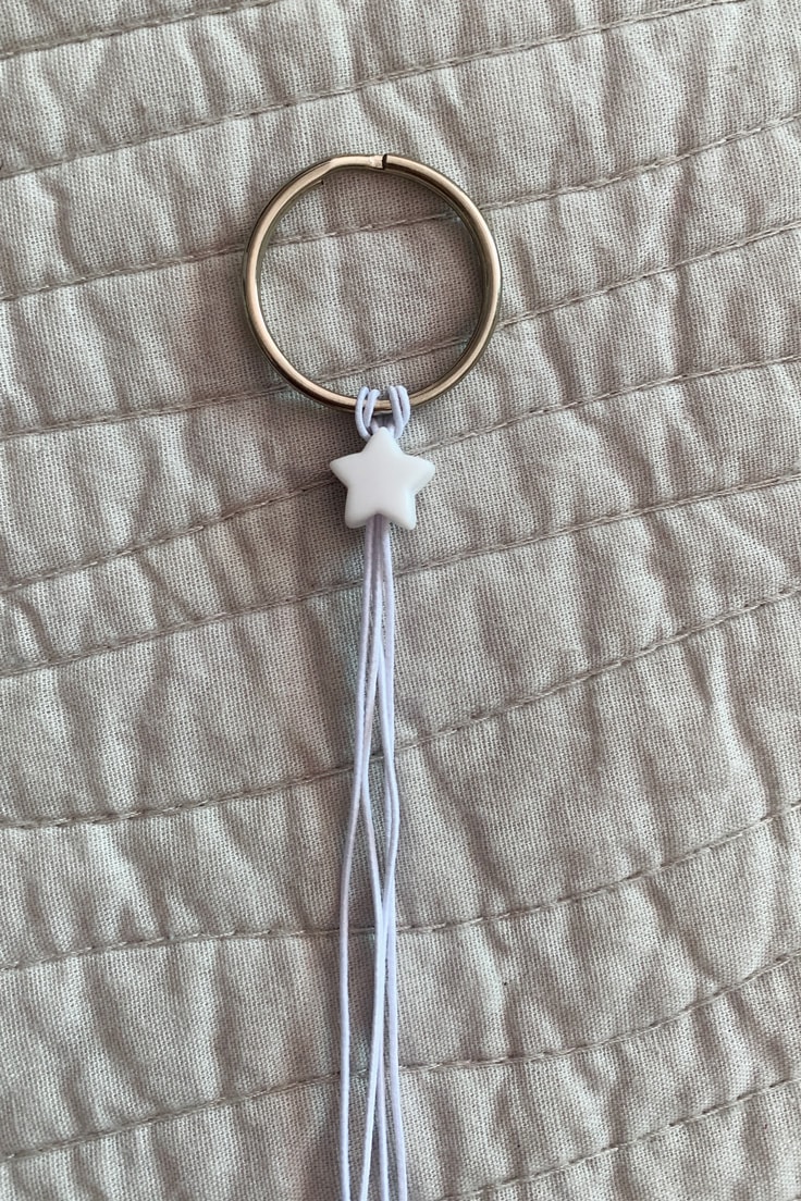 A white star bead threaded onto elastic cord against a keyring.