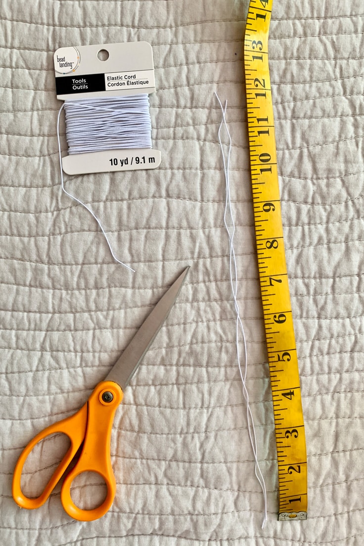 Two strands of 12-inch elastic cord between a pair of scissors and a fabric tape measure.
