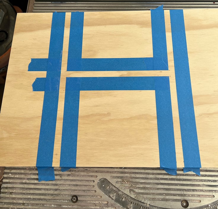blue painters tape is applied to the project panel to create a stencil for painting the design on the basketball hoop backboard.