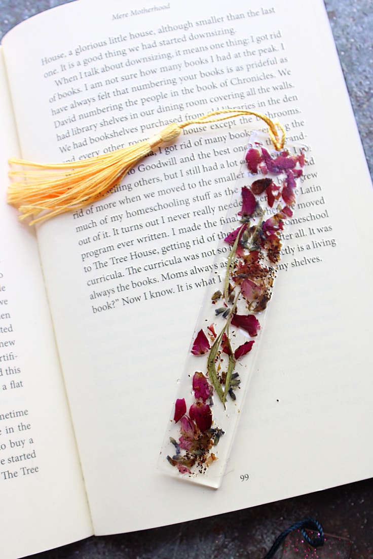 flower resin bookmark lying on open page of a book with text
