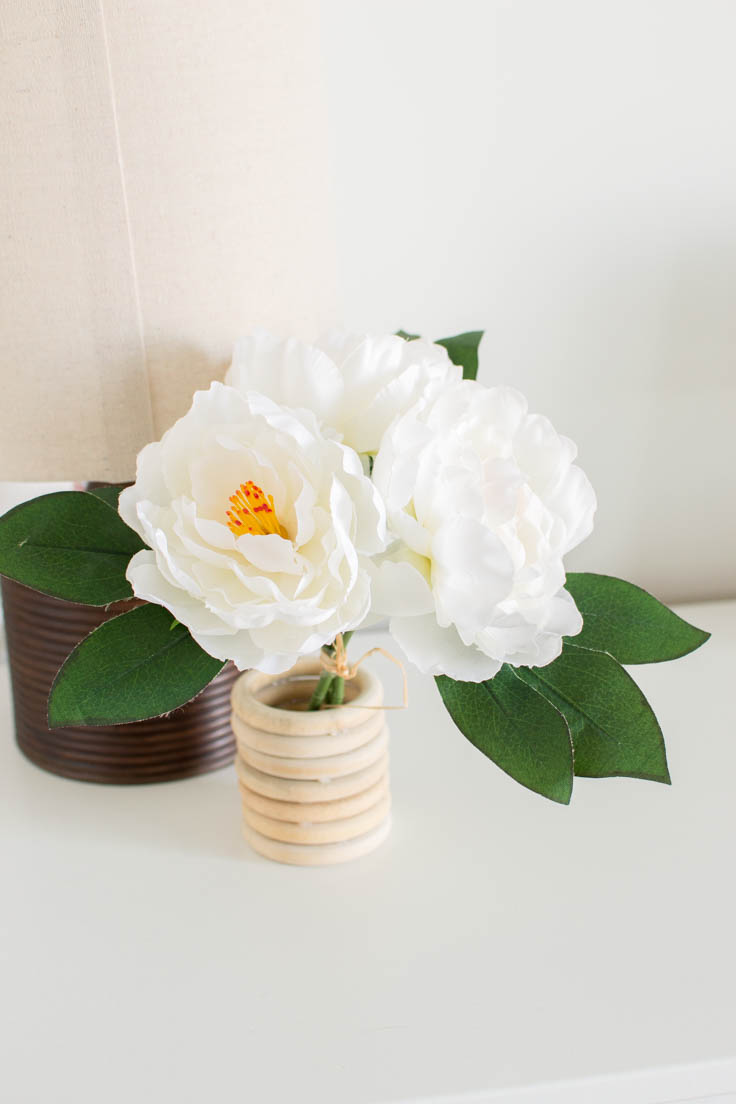 Faux white flowers sitting in a DIY wooden vase