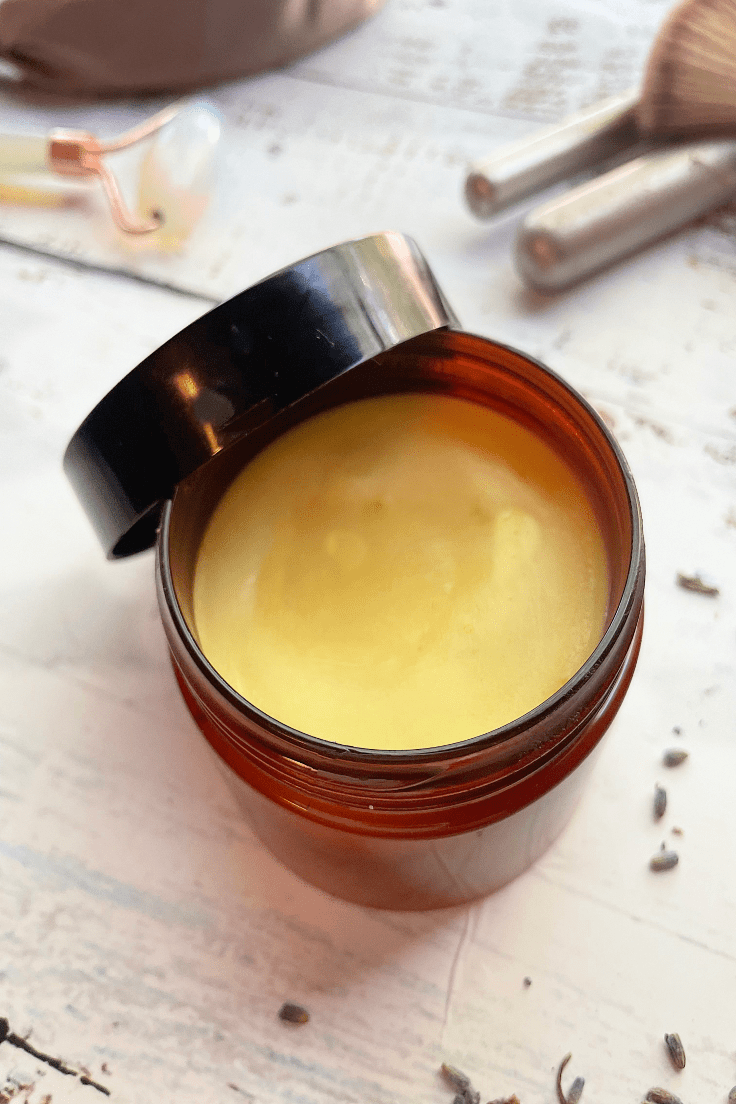 DIY face moisturizer in a jar on white wood with makeup brushes